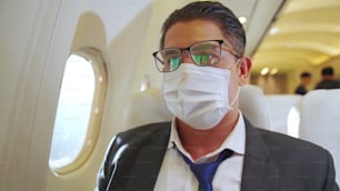 Viajero con mascarilla mientras viaja en avión comercial. Concepto de enfermedad por coronavirus o efectos del brote de la pandemia de COVID 19 en el turismo y el negocio de las aerolíneas.