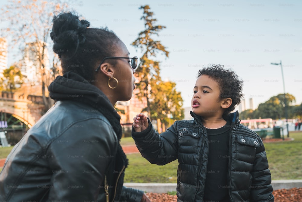Retrato de una madre afroamericana con su hijo parado al aire libre en el parque, divirtiéndose. Familia monoparental.