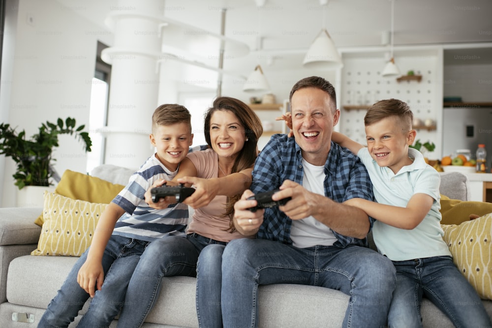 Husband and wife playing video games with joysticks in living room. Loving couple are playing video games with kids at home"t