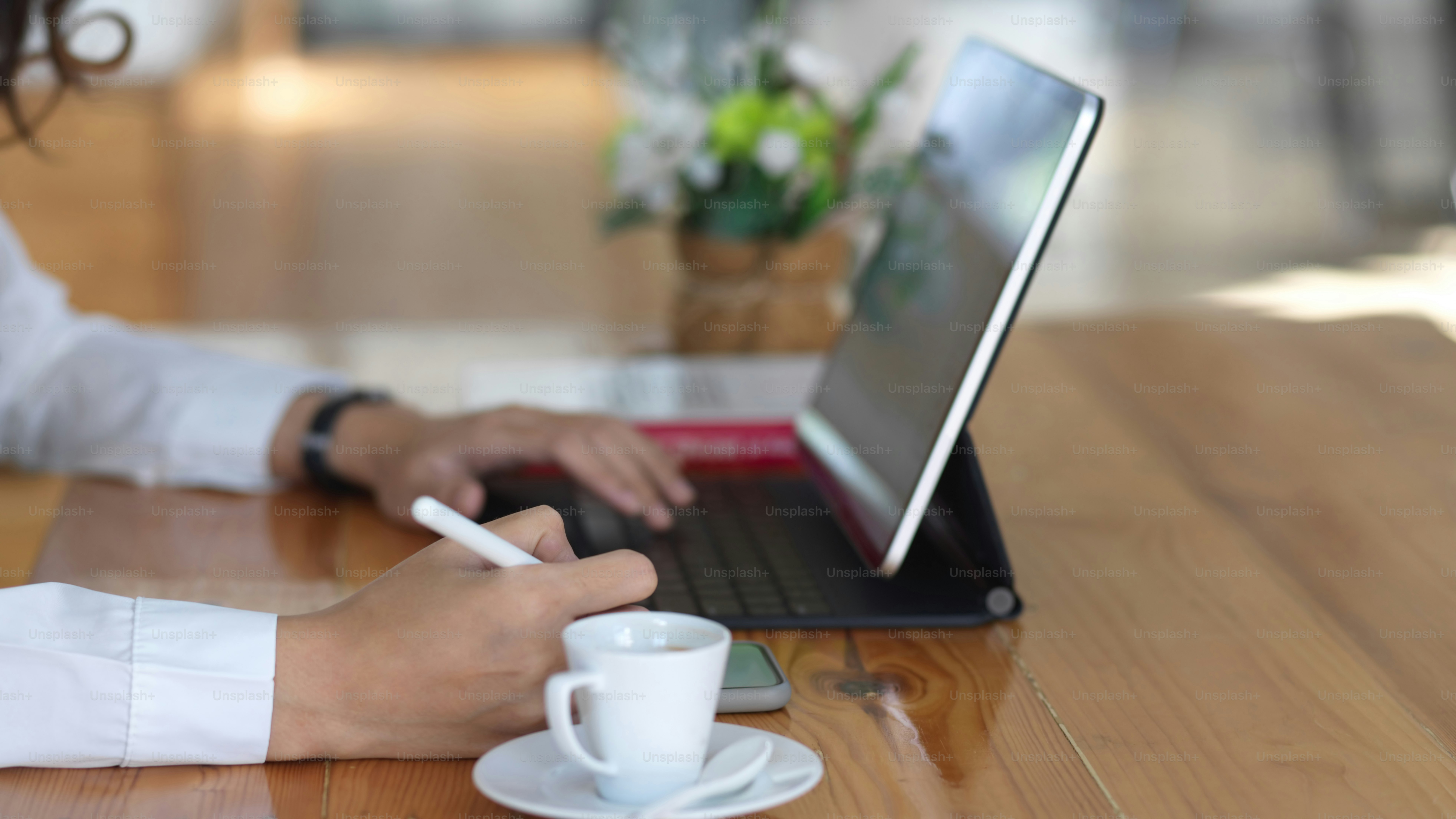 Side view of female hands working with digital tablet and stationery on wooden table