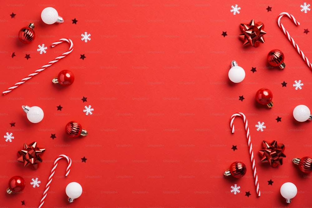 Sfondo natalizio rosso con decorazioni di palline rosse e bianche, bastoncini di zucchero e coriandoli. Modello di cartolina di Natale, mockup di banner.