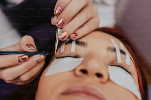 Beautiful young woman at eyelash extension procedure. Cosmetics and body care close up shot.