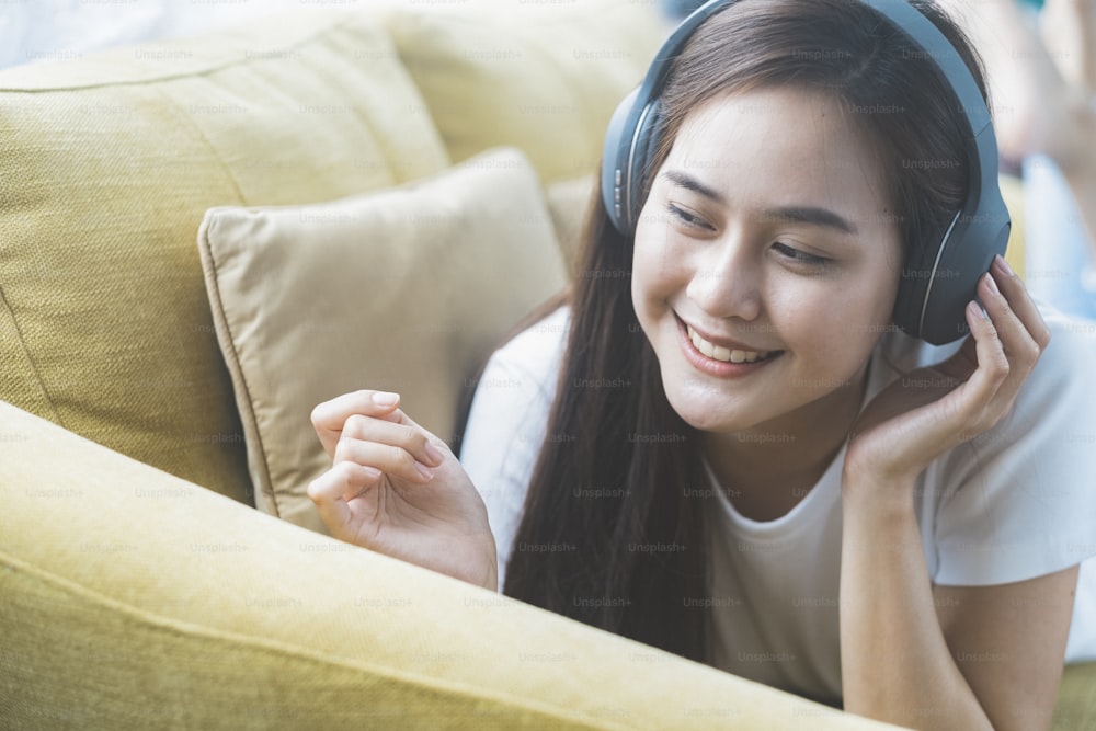 Young woman listening to music  lying on sofa in room.