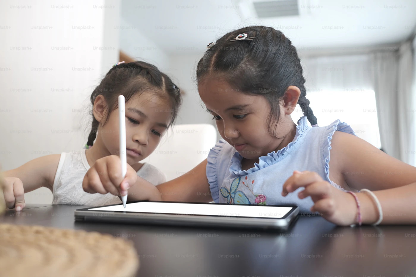 Two children creating digital art together with a tablet and stylus