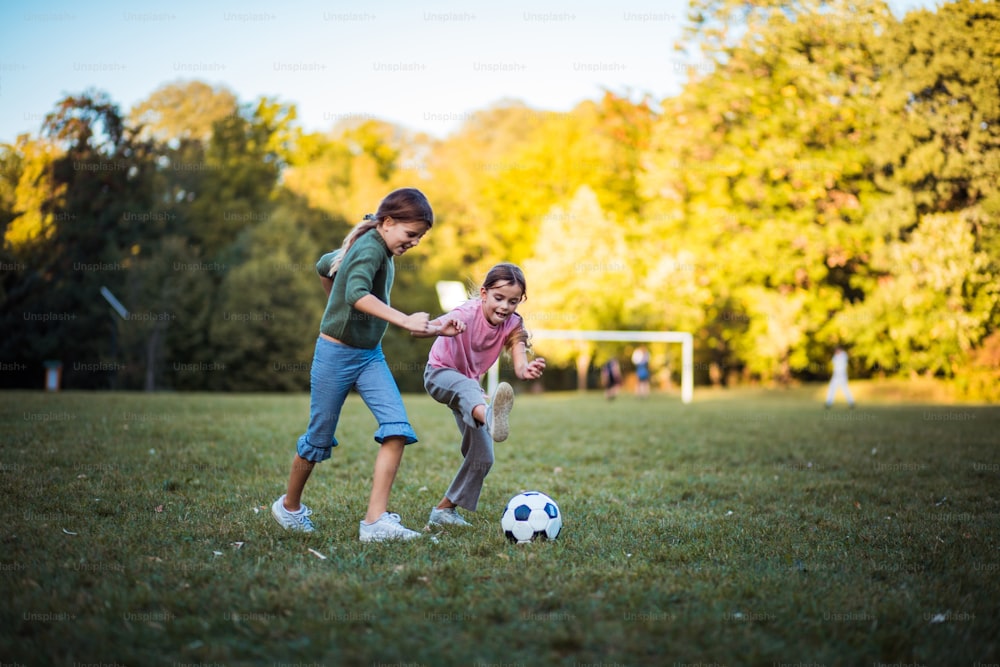 Schwesterwettbewerb.  Zwei kleine Mädchen spielen Fußball. Aufschließen.