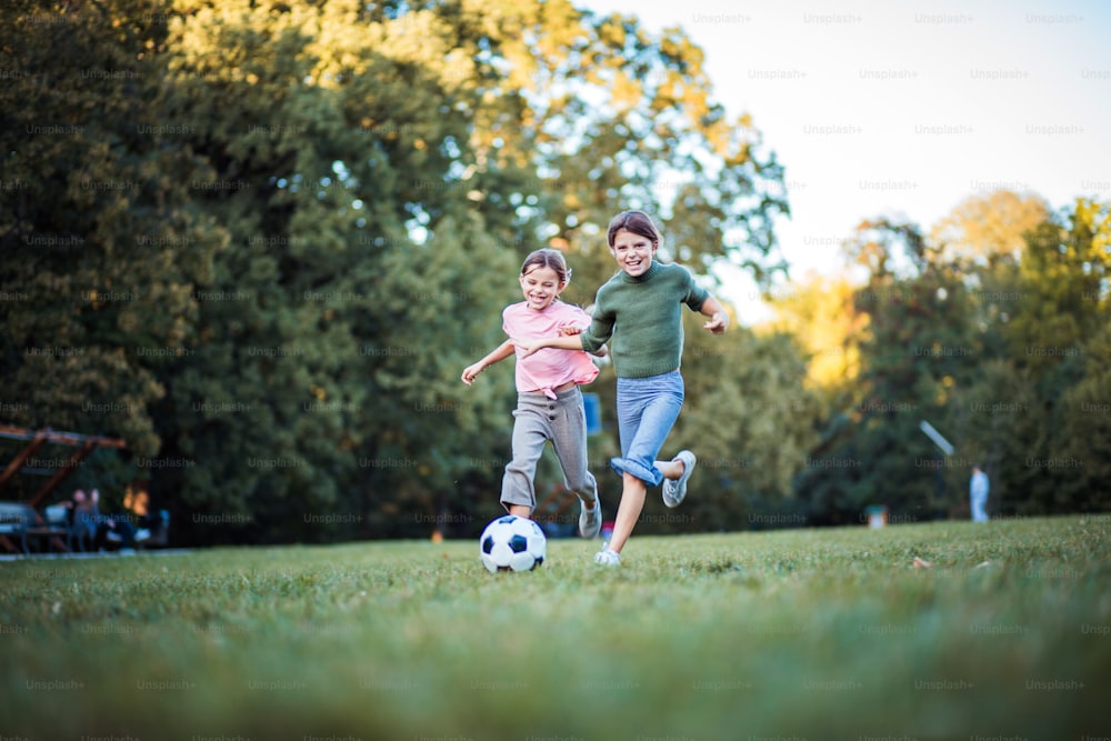 Freunde-Wettbewerb.  Zwei kleine Mädchen spielen Fußball. Aufschließen.