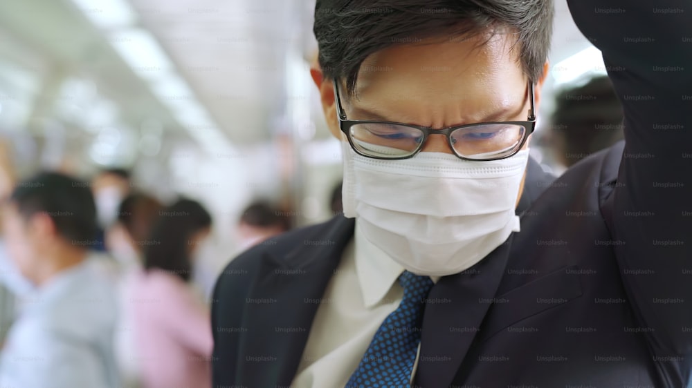 Junger Mann mit Gesichtsmaske fährt in überfüllter U-Bahn. Coronavirus-Krankheit oder COVID-19-Pandemie-Ausbruch und städtisches Lebensstilproblem im Berufsverkehrskonzept.