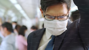 Young man wearing face mask travels on crowded subway train . Coronavirus disease or COVID 19 pandemic outbreak and urban lifestyle problem in rush hour concept .