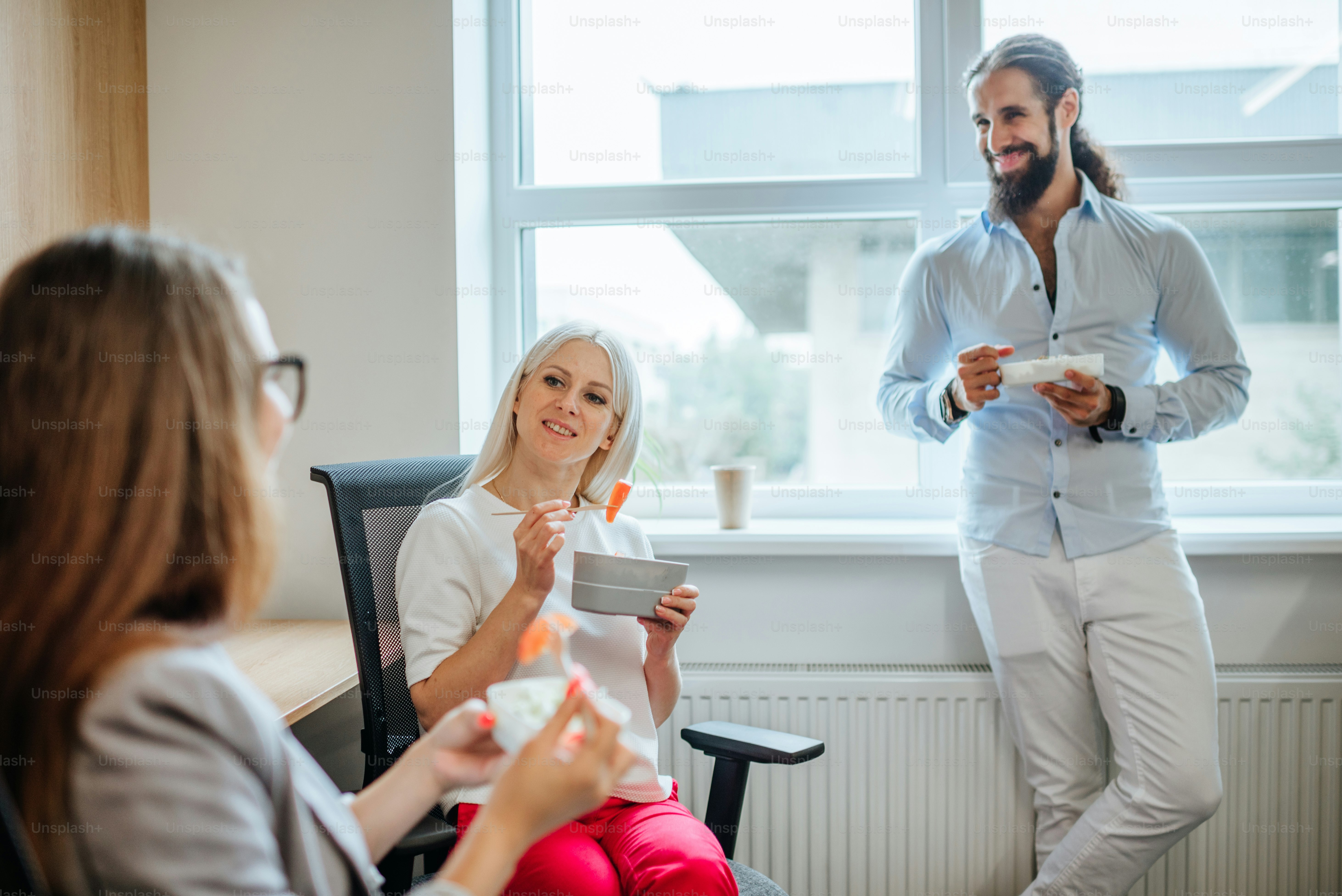 Uma hora de almoço no escritório. Três pessoas de negócios almoçando em lancheiras no espaço de trabalho moderno.