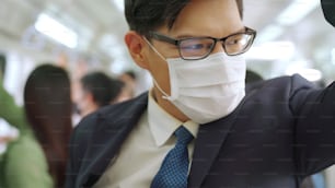 マスクを着けた若い男性が満員の地下鉄で移動します。コロナウイルス病またはCOVID19パンデミックの発生とラッシュアワーのコンセプトにおける都市ライフスタイルの問題。