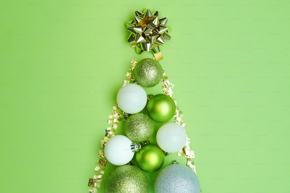メリークリスマス。緑の背景にクリスマスボールとクリスマスツリーを平らに敷き詰めました。