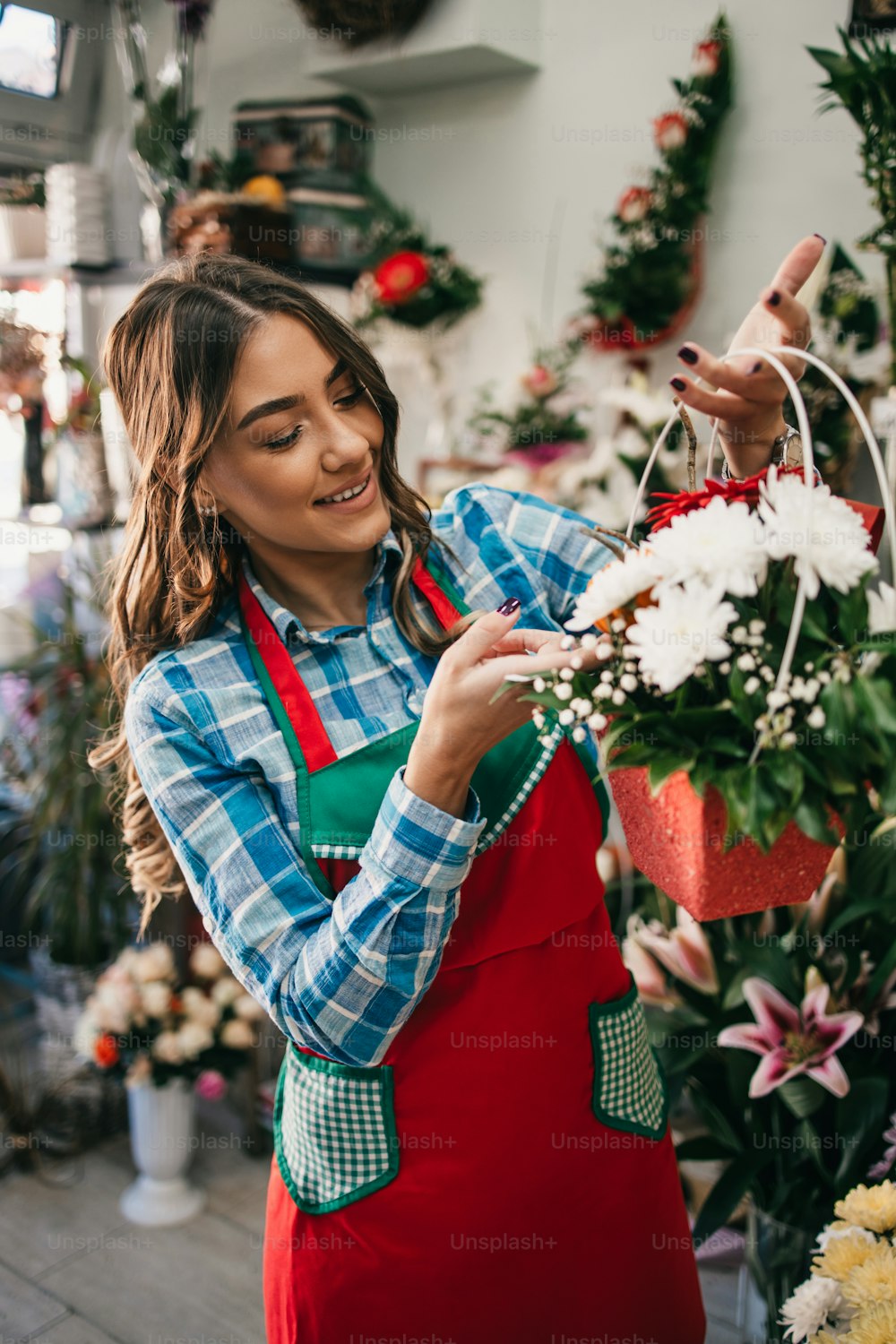Junge erwachsene Frau, die in einem Blumenladen oder Floristen arbeitet. Konzept für kleine Unternehmen.