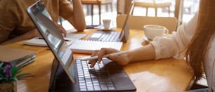 Seitenansicht der weiblichen Hand, die während der Arbeit an einem Gruppenprojekt auf der Tablet-Tastatur tippt
