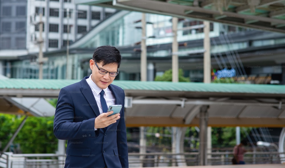 Asian businessman walking in the city with using smartphone