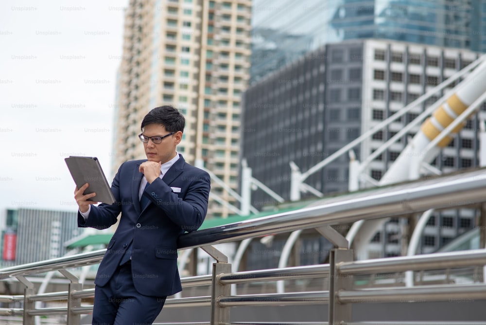 Asian businessman walking in the city with using digital tablet