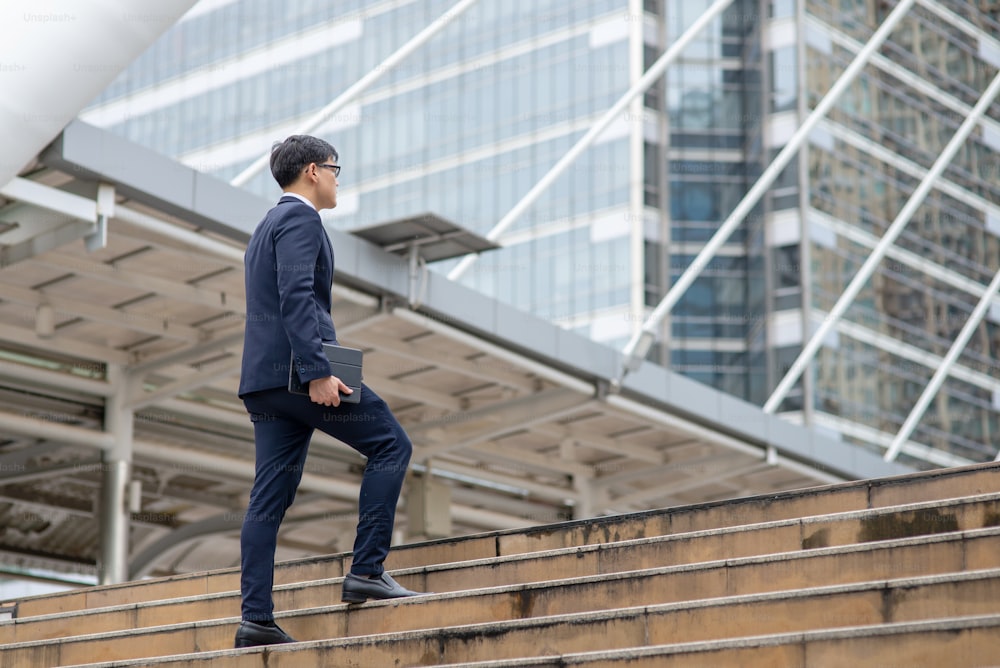 Hombre de negocios asiático subiendo las escaleras de la ciudad.