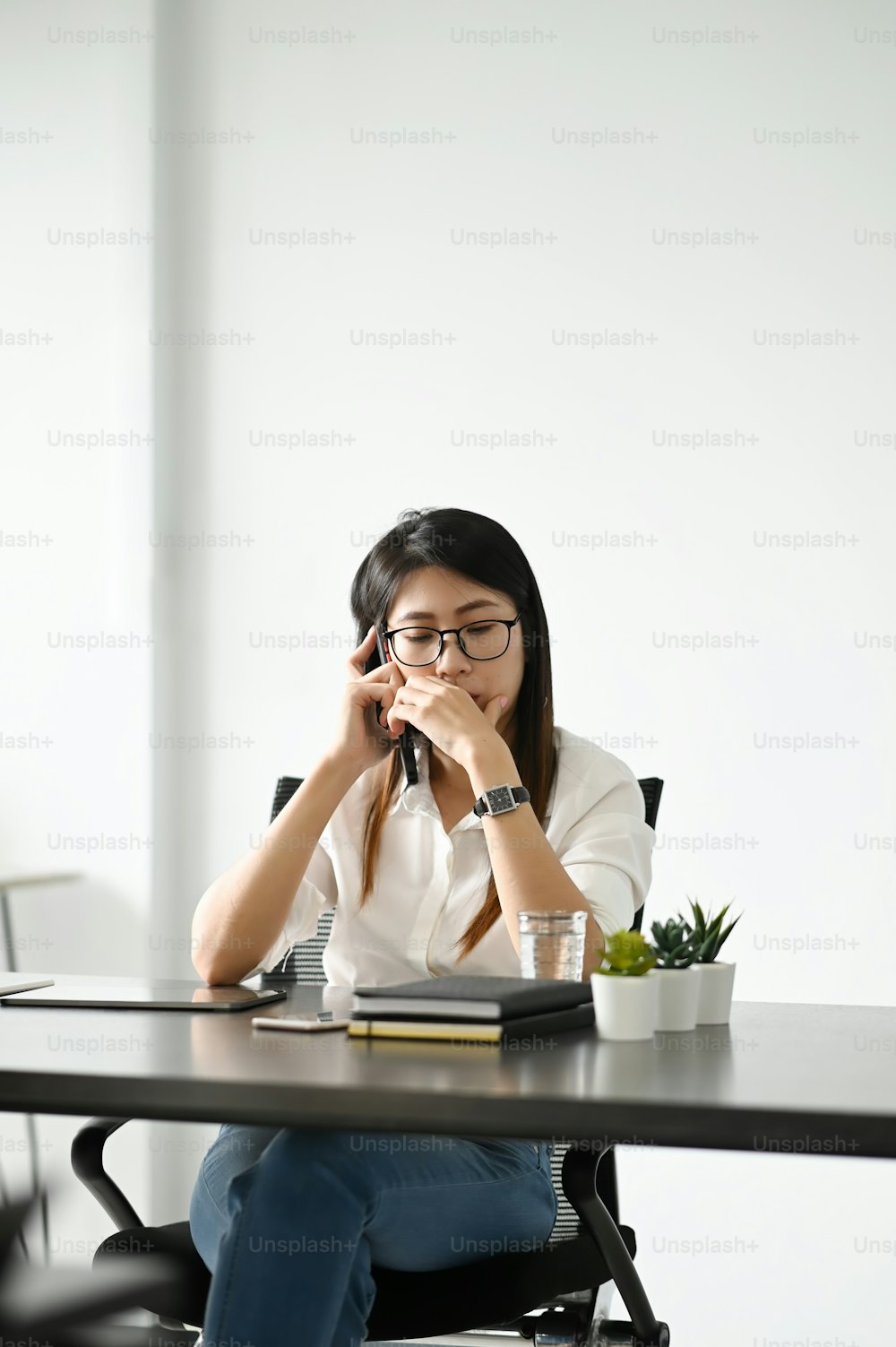 A businesswoman talking on mobile phone while sitting her work space.