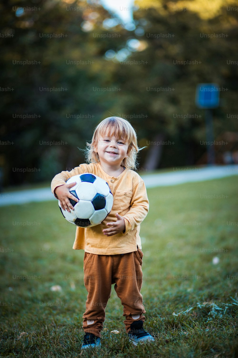 Pequeno jogador de bola de pé. Garotinho com bola de futebol na grama.