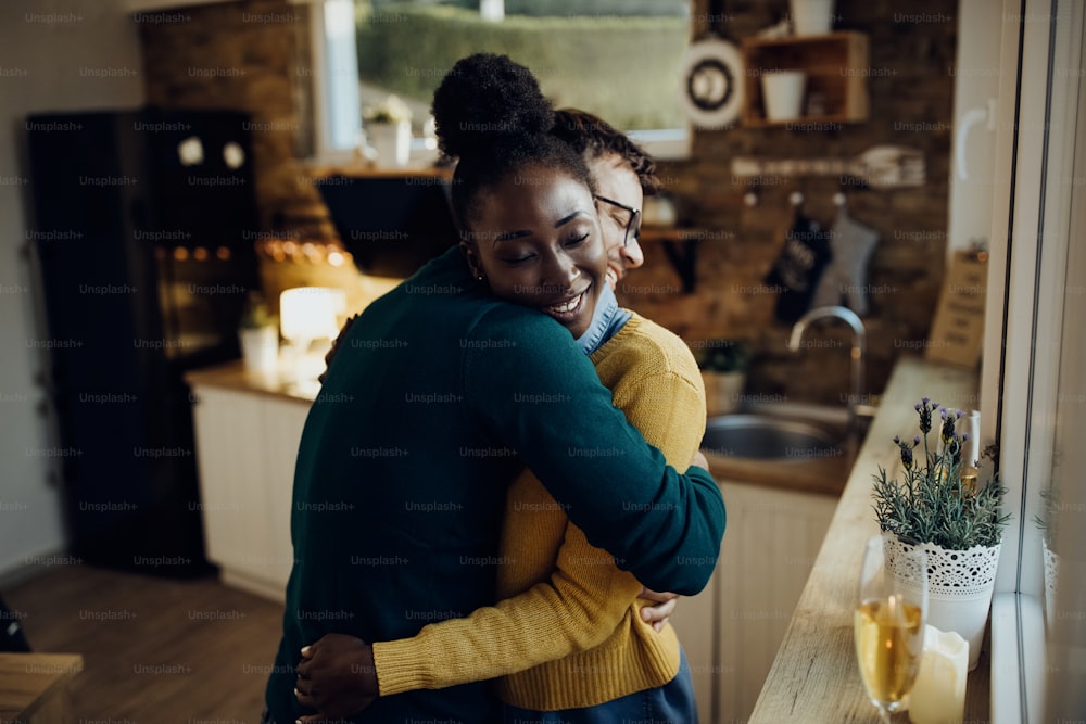 아프리카계 미국인 여성과 그녀의 남자친구가 집에서 눈을 감고 포옹하고 있다.