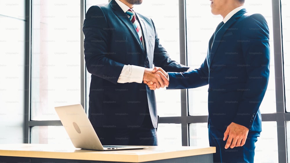 Des gens d’affaires se serrent la main dans un bureau d’entreprise montrant un accord professionnel sur un contrat d’accord financier.