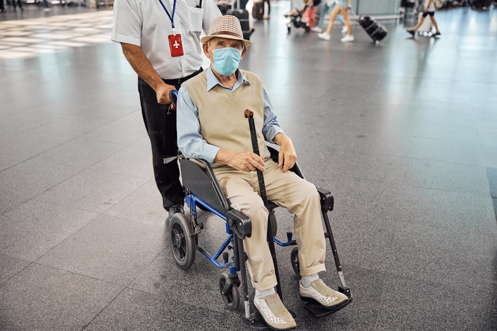 Front view of a senior Caucasian man sitting in a wheelchair at an airport terminal