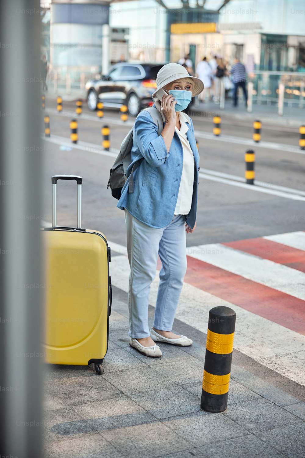 Retrato de corpo inteiro de uma mulher turista em uma máscara de proteção fazendo um telefonema ao ar livre