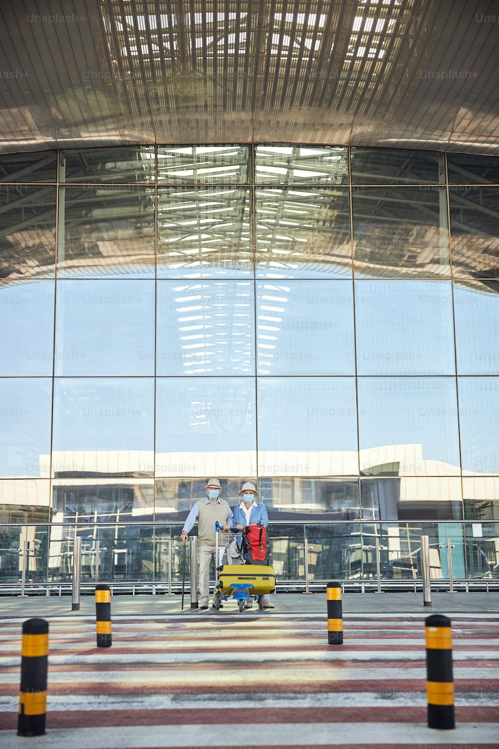 Front view of an elderly couple with the baggage trolley staring in front of them