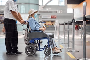 Side view of a disabled airline passenger being transported to an airplane by an experienced employee
