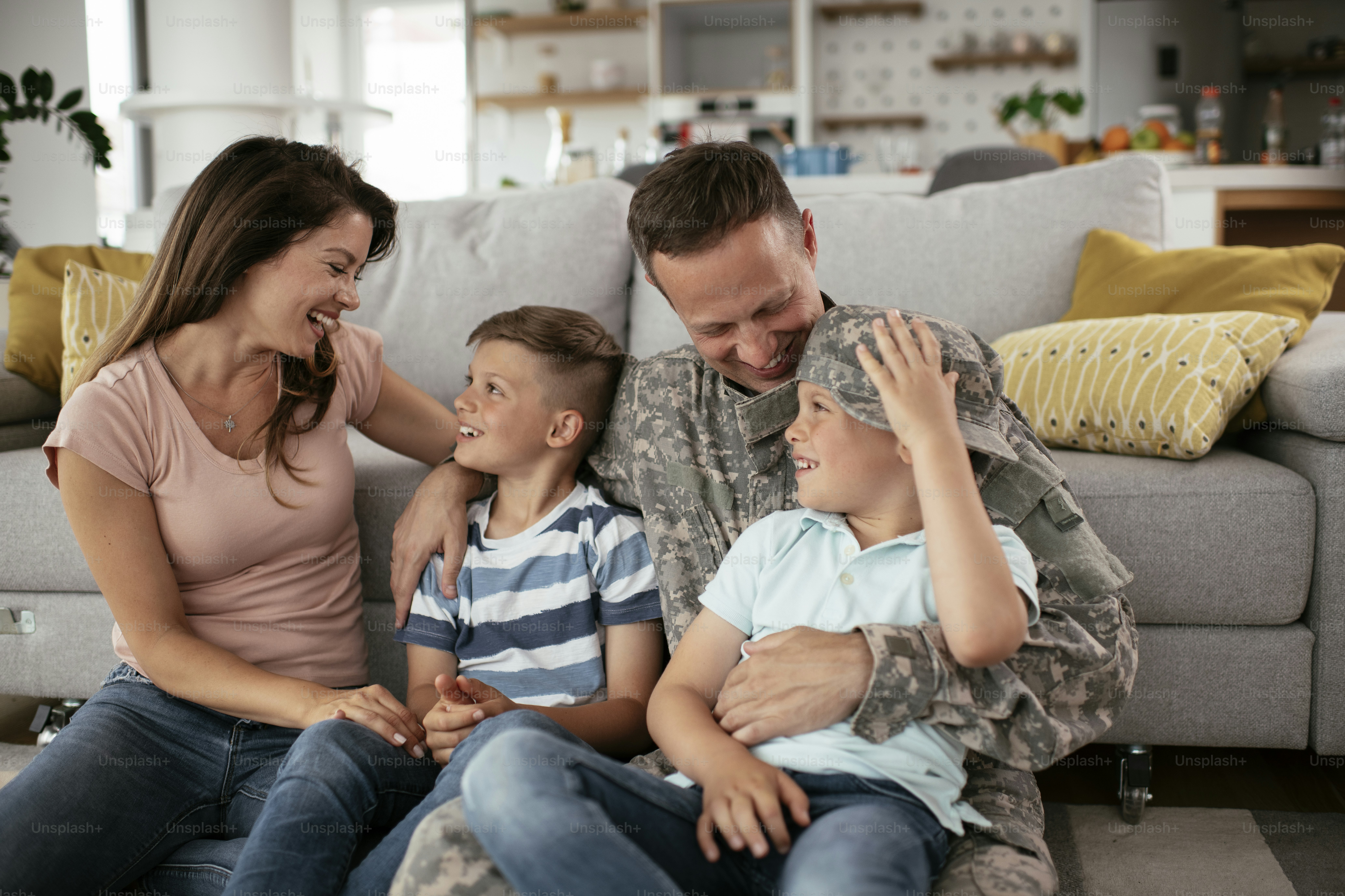 Soldado feliz sentado no chão com sua família. Soldado e sua esposa desfrutando em casa com os filhos