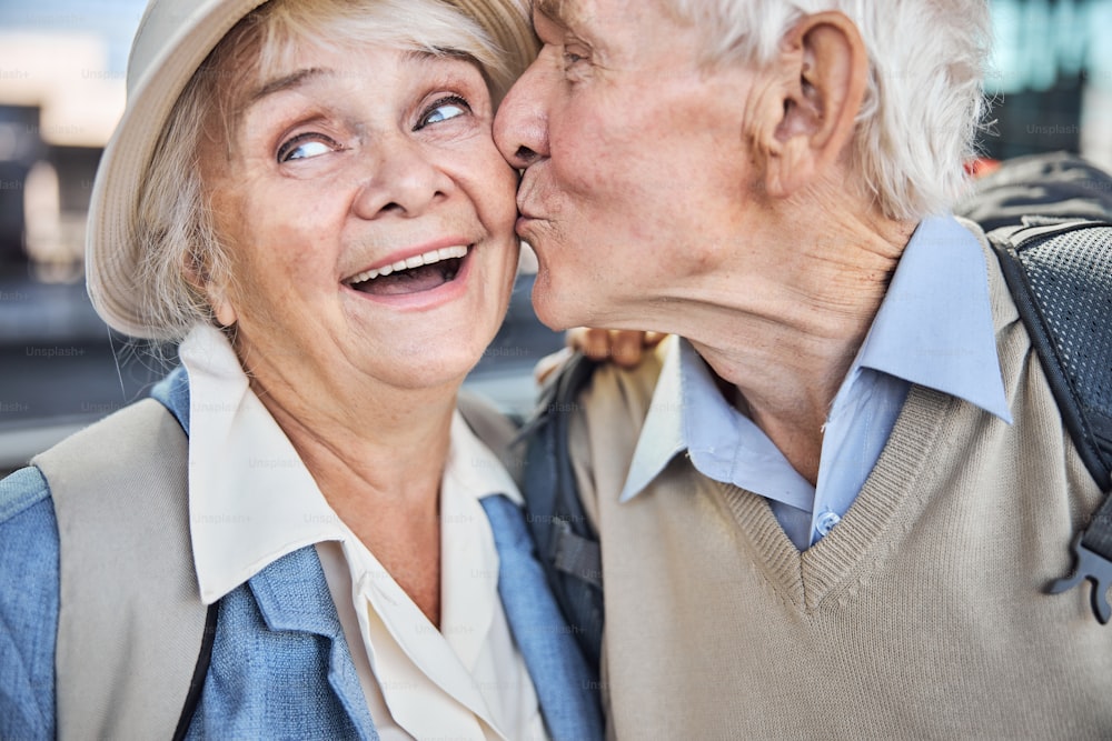 Close up portrait of a romantic aged man giving a tender kiss to his beautiful wife