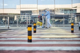 Side view of a senior Caucasian lady tourist and her husband wheeling the baggage trolley