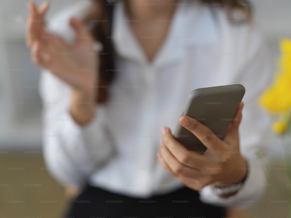 Close up view of female hand holding smartphone in blurred background
