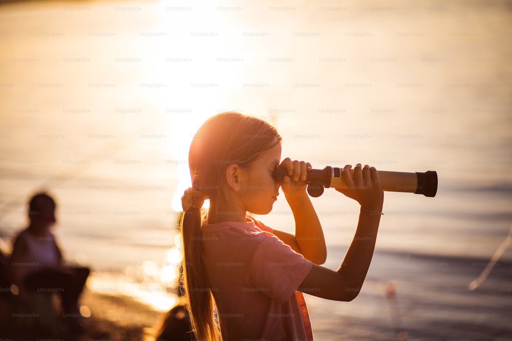 Little researcher. Little girl looking through telescope outside