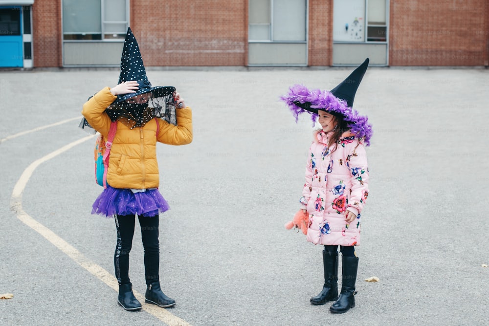 Felice Halloween. Bambini, ragazze, amiche in costume e maschere protettive per il viso che vanno a scuola. Studenti della scuola della gente che celebrano la festa di Halloween. Una nuova normalità ai tempi del coronavirus.