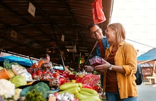 Beau jeune couple achetant des légumes frais sur le marché en plein air.