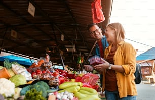 Schönes junges Paar, das frisches Gemüse auf dem Outdoor-Markt kauft.