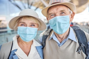 Front view of a senior tourist couple in protective masks looking in front of them