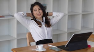 Young businesswoman stretching her arms after a busy day at work, businesswoman taking a rest in the office room