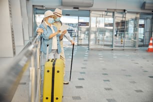 Retrato de cuerpo entero de una anciana y su cónyuge de pie con su equipaje en el aeropuerto