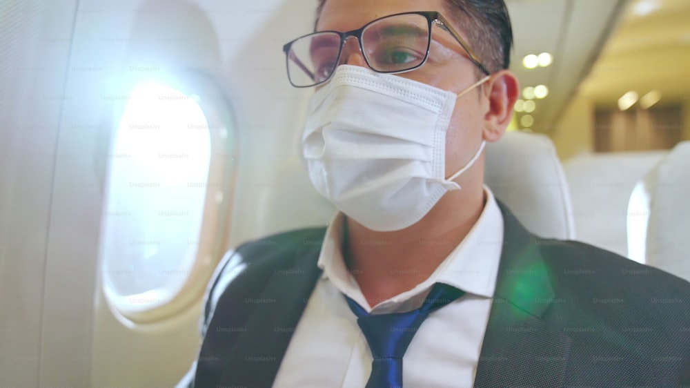상업용 비행기를 타고 여행하는 동안 안면 마스크를 착용한 여행자. 코로나 바이러스 질병 또는 COVID 19 전염병 발생이 관광 및 항공 사업에 미치는 영향의 개념.