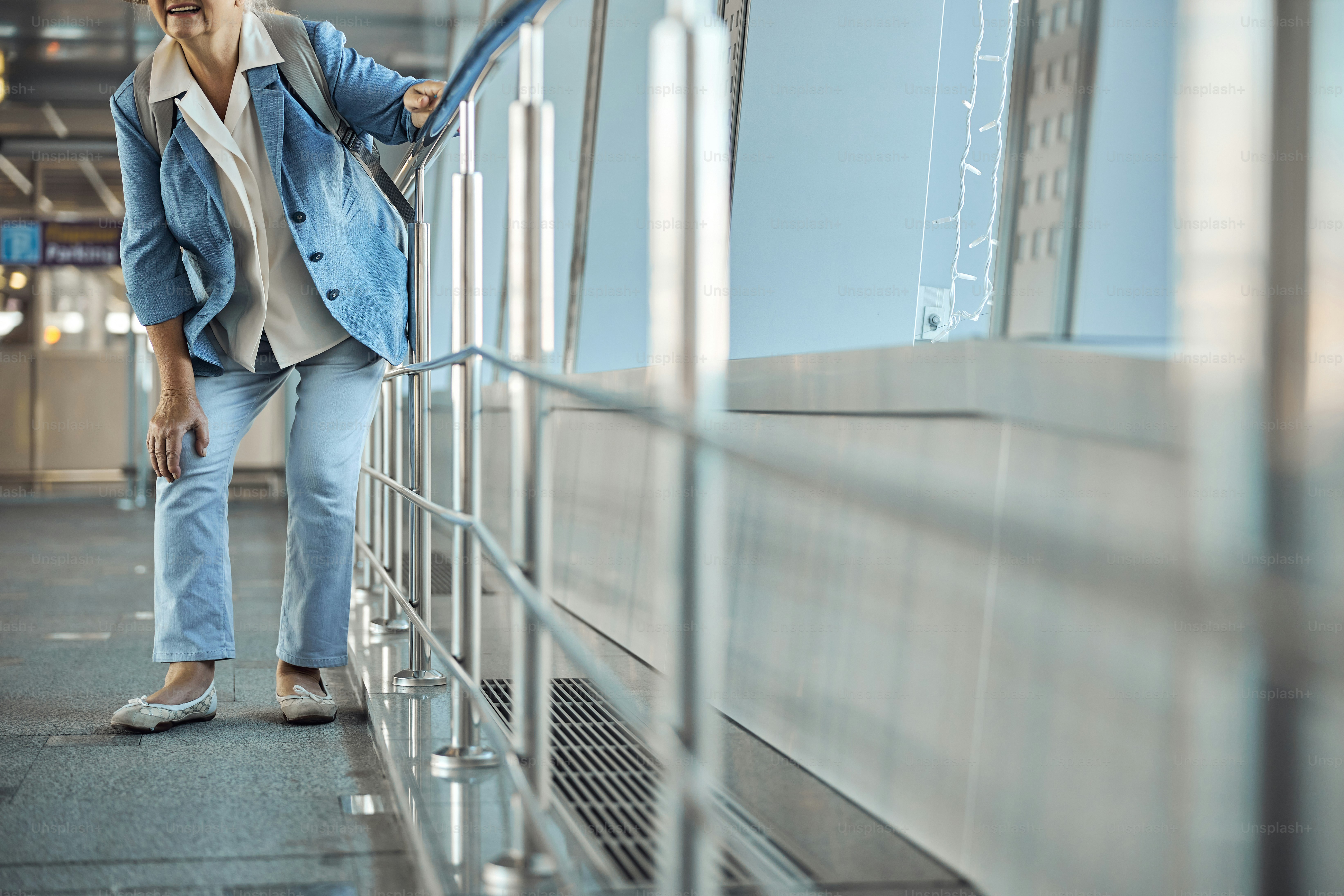 Cropped photo of a senior female tourist experiencing an acute joint pain at the airport terminal