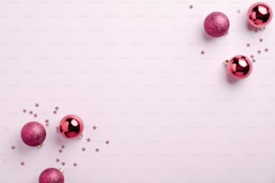 Pink Christmas background with balls decoration and confetti on pink. Flat lay, top view. Xmas postcard template, beauty blog banner mockup.