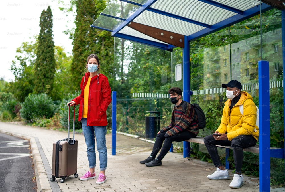 Young people on bus stop outdoors in town. Coronavirus and safe distance concept.