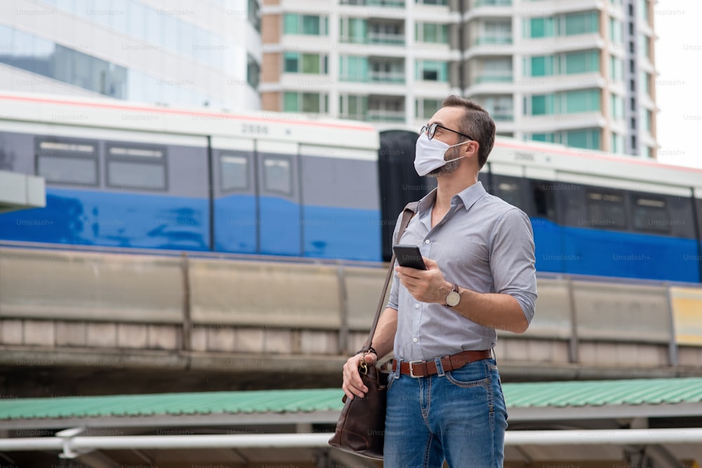 Caucasian man wearing protective face mask using smartphone in the city