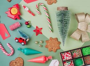 Christmas gingerbread cookies, icing bags, sprinkling and decor on green colorblock background. Top view, flat lay.