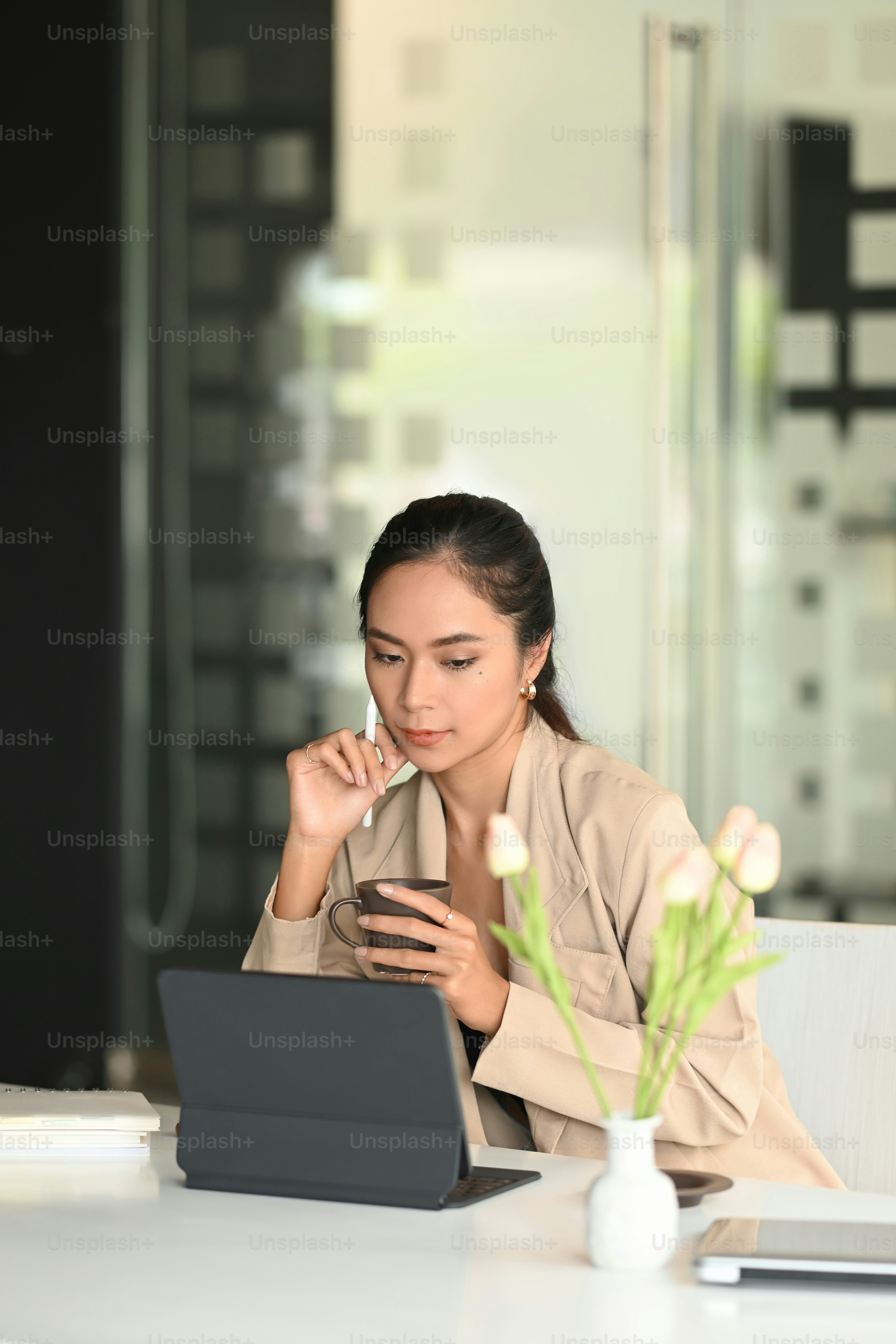 Um empreendedor experiente está lendo algum texto em tablet enquanto bebe café no escritório.