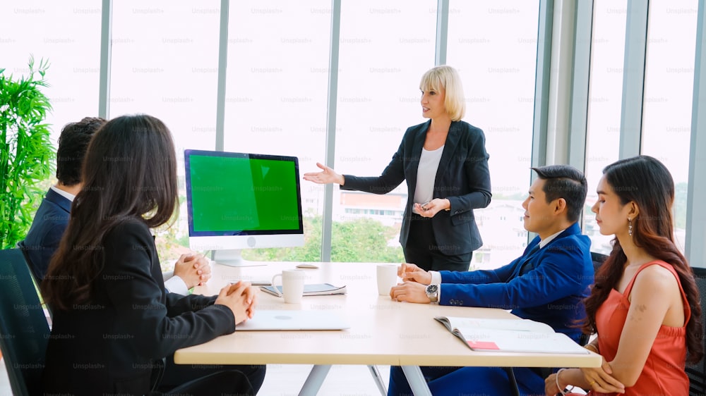 Gente de negocios en la sala de conferencias con pantalla verde chroma key TV o computadora en la mesa de la oficina. Grupo diverso de empresarios y empresarias reunidos en videoconferencia.
