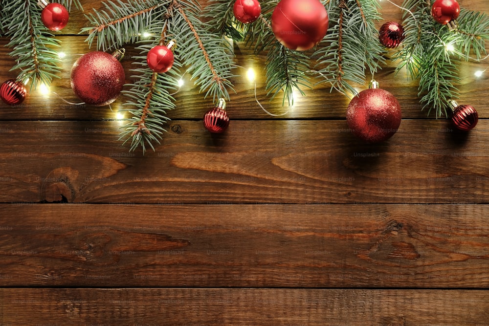Fundo de Natal de madeira com decorações, enfeites vermelhos, galhos de abeto, guirlanda. Celebração do feriado de Natal, inverno, conceito de Ano Novo. Maquete de banner de Natal, modelo de cartão de felicitações