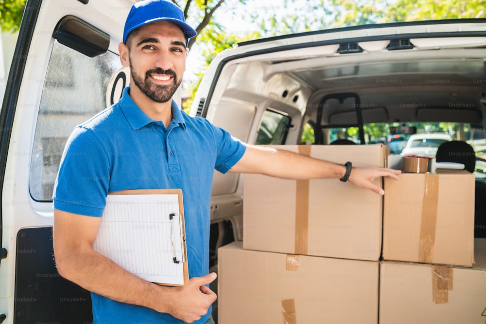 Portrait of a delivery man checking the products in checklist while standing right next to his van. Delivery and shipping concept.