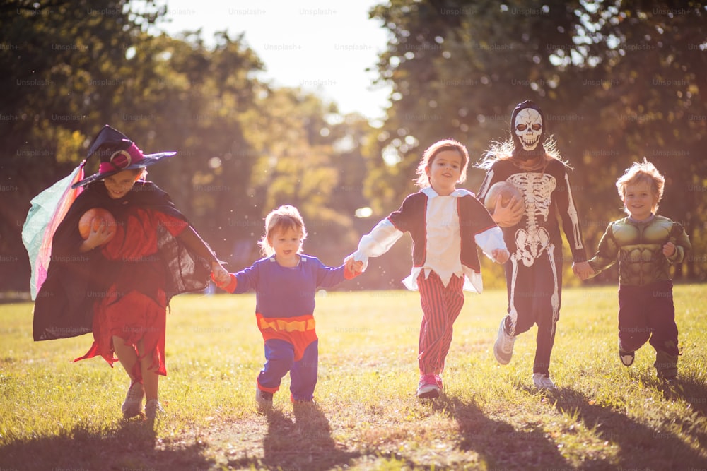 Dia engraçado.  Crianças em ternos de Halloween correm pelo parque.